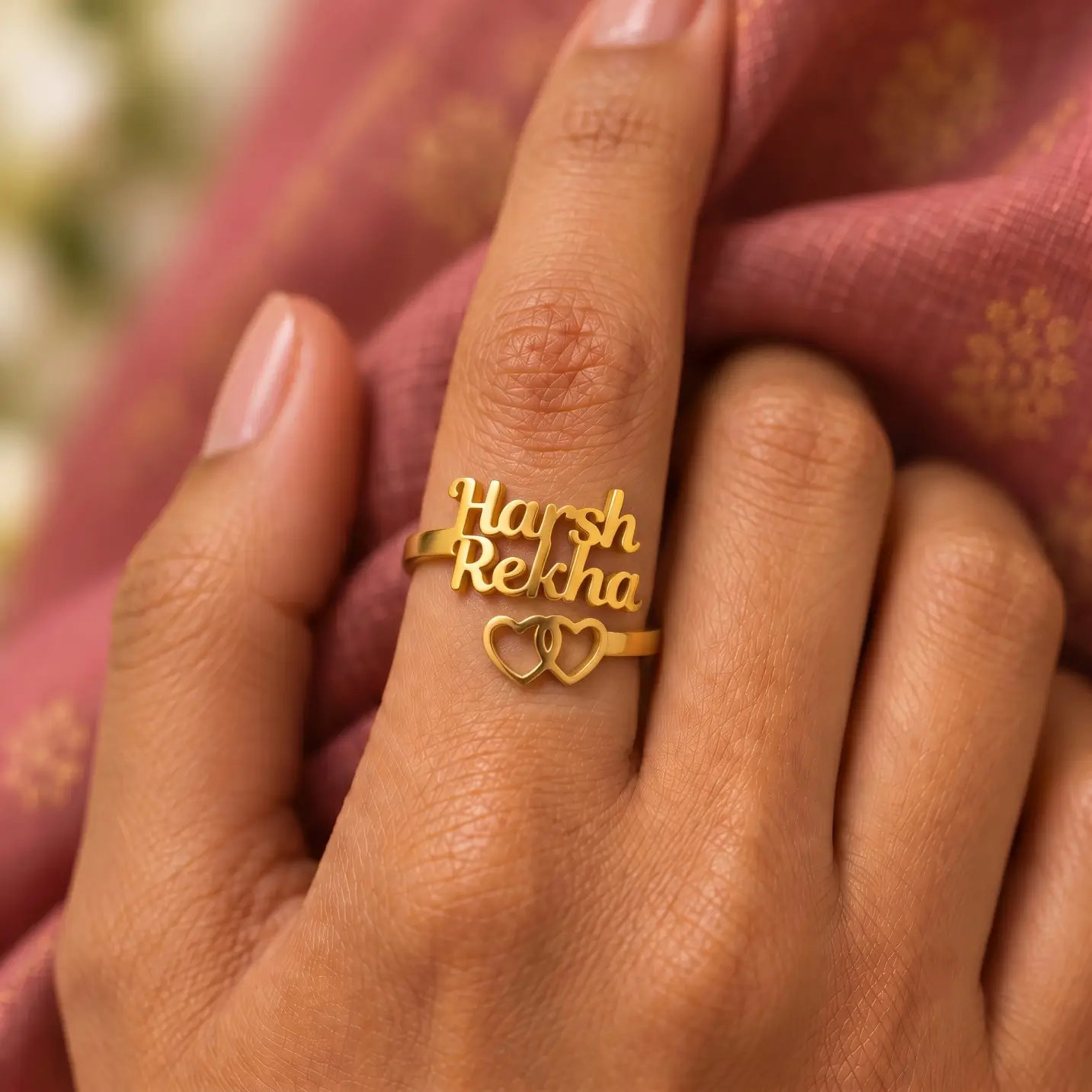 Two Hearts Personalized Love Ring – Image 1 Two Hearts Personalized Love Ring worn on a hand against rose-coloured fabric