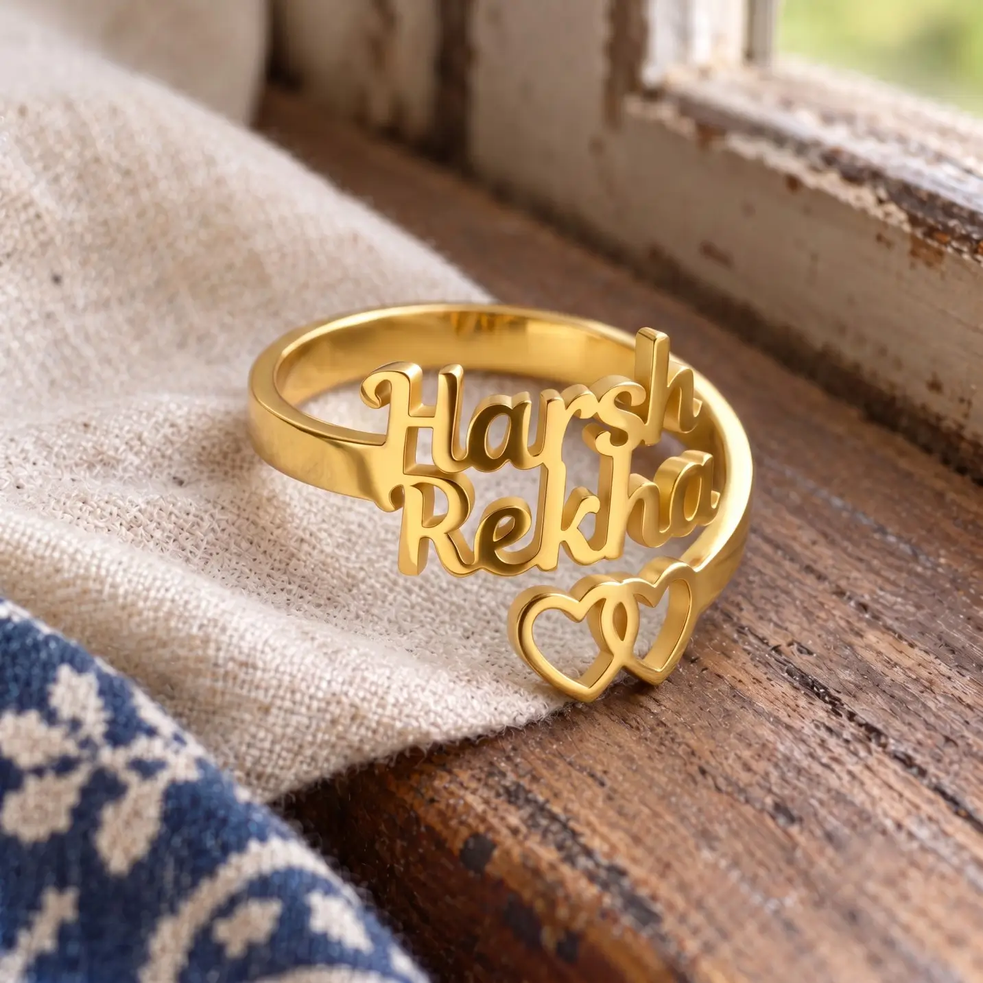 Two Hearts Personalized Love Ring – Image 3 Two Hearts Personalized Love Ring displayed on beige linen beside a wooden window