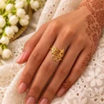 Two Hearts Personalized Love Ring worn on a hand with mehndi beside white embroidered fabric