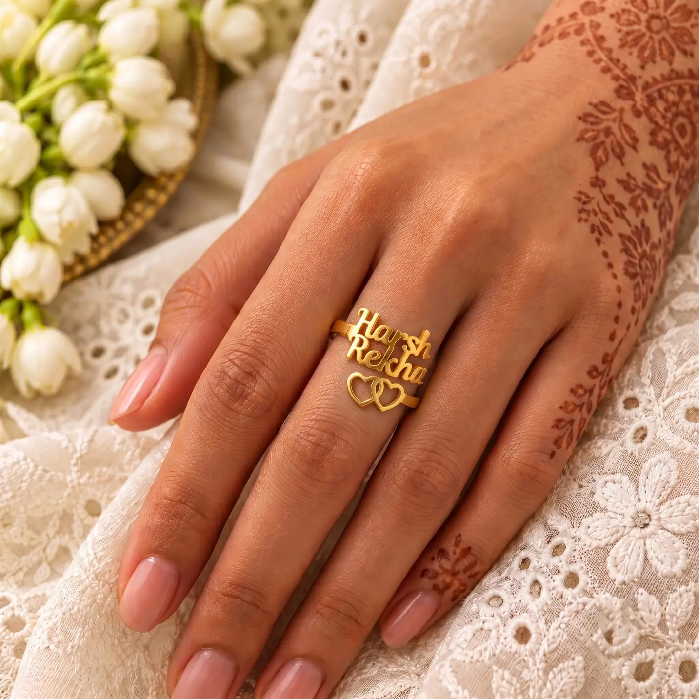 Two Hearts Personalized Love Ring – Image 4 Two Hearts Personalized Love Ring worn on a hand with mehndi beside white embroidered fabric