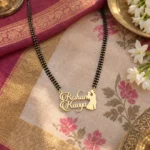 Romantic Couple Name Mangalsutra Pendant with a black-beaded chain on floral fabric