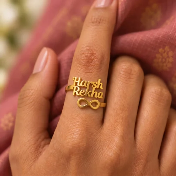 Personalized Infinity Couple Name Ring worn on a hand against rose-coloured fabric