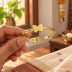 Golden Butterfly Link Bracelet held in a hand showing the front design and hinged fastening