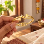 Golden Double Heart Cuff Bracelet held in a hand showing the front design and hinged fastening