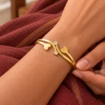 Golden Double Heart Cuff Bracelet worn on a wrist against maroon fabric