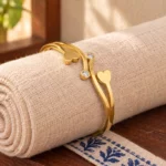Golden Double Heart Cuff Bracelet displayed around a rolled ivory linen cloth