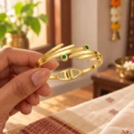 Golden Green Stone Leaf Cuff Bracelet held in a hand showing the front design and hinged fastening
