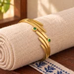 Golden Green Stone Leaf Cuff Bracelet displayed around a rolled ivory linen cloth