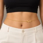 Gold-tone personalized Niyaa waist chain worn with a black top and ivory trousers