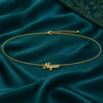 Personalized Niyaa cursive name waist chain with adjustable clasp displayed on teal fabric