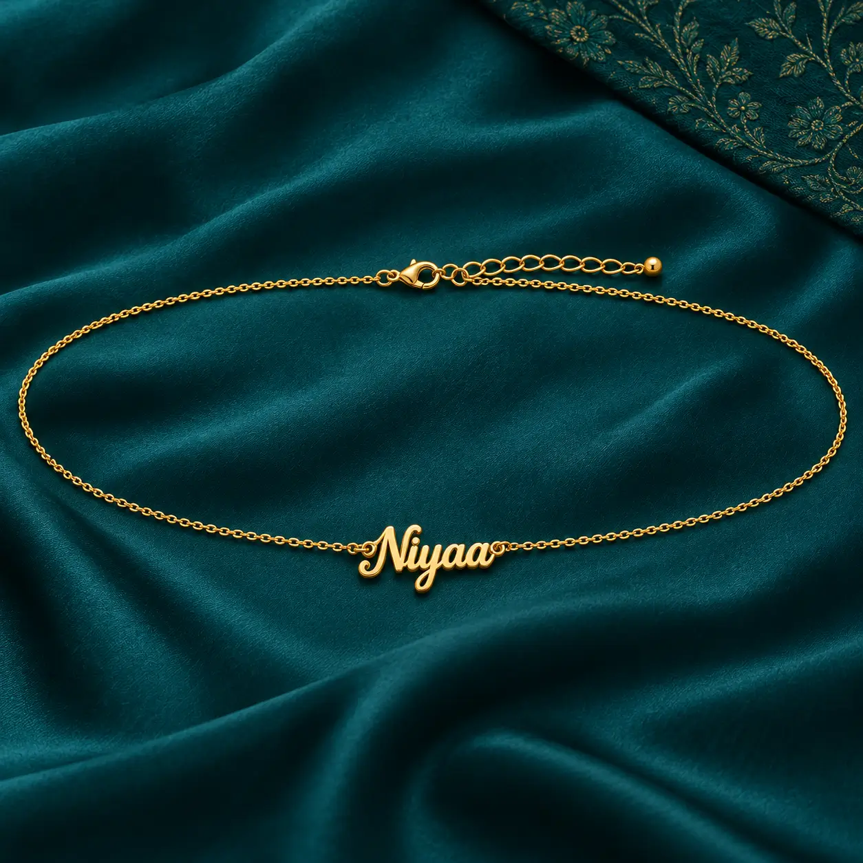 Personalized Cursive Name Waist Chain - Teal Fabric Flat Lay Personalized Niyaa cursive name waist chain with adjustable clasp displayed on teal fabric