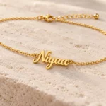 Close-up of gold-tone Niyaa cursive nameplate and fine links on a personalized waist chain