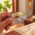 Golden oval nameplate and silver-tone mesh band of a personalized engraved bracelet held in hand